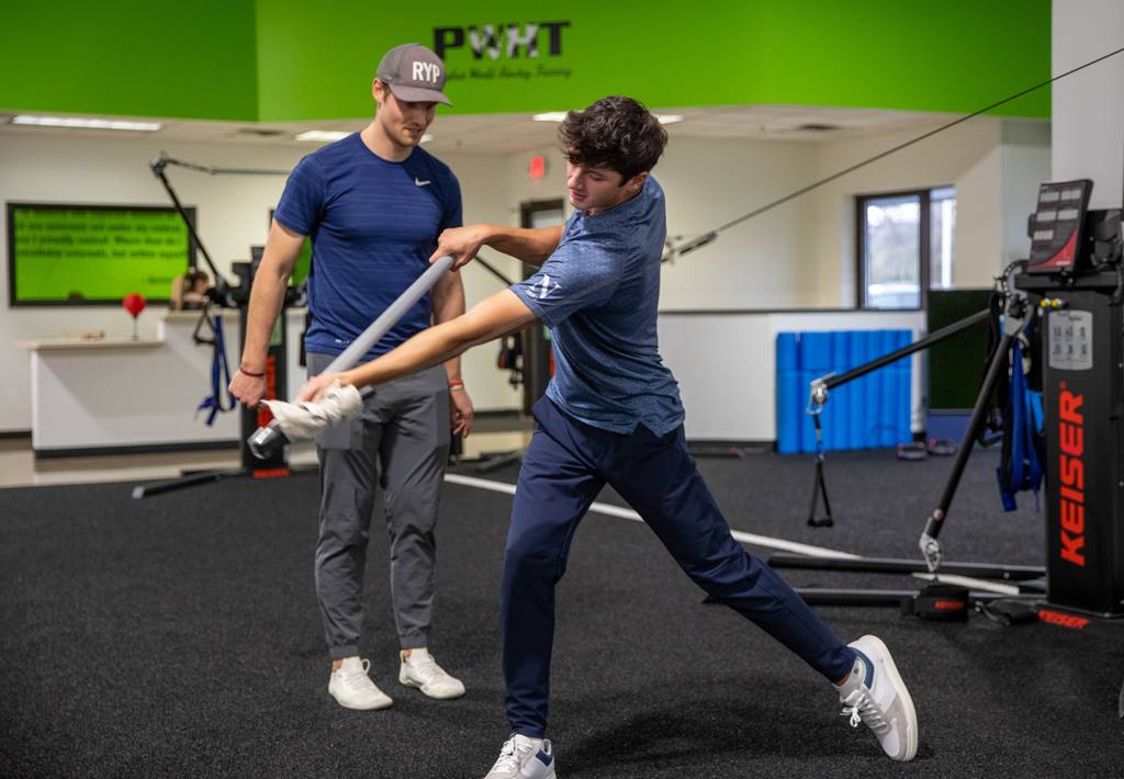 A junior athlete working through resistance-band rotation in the performance gym